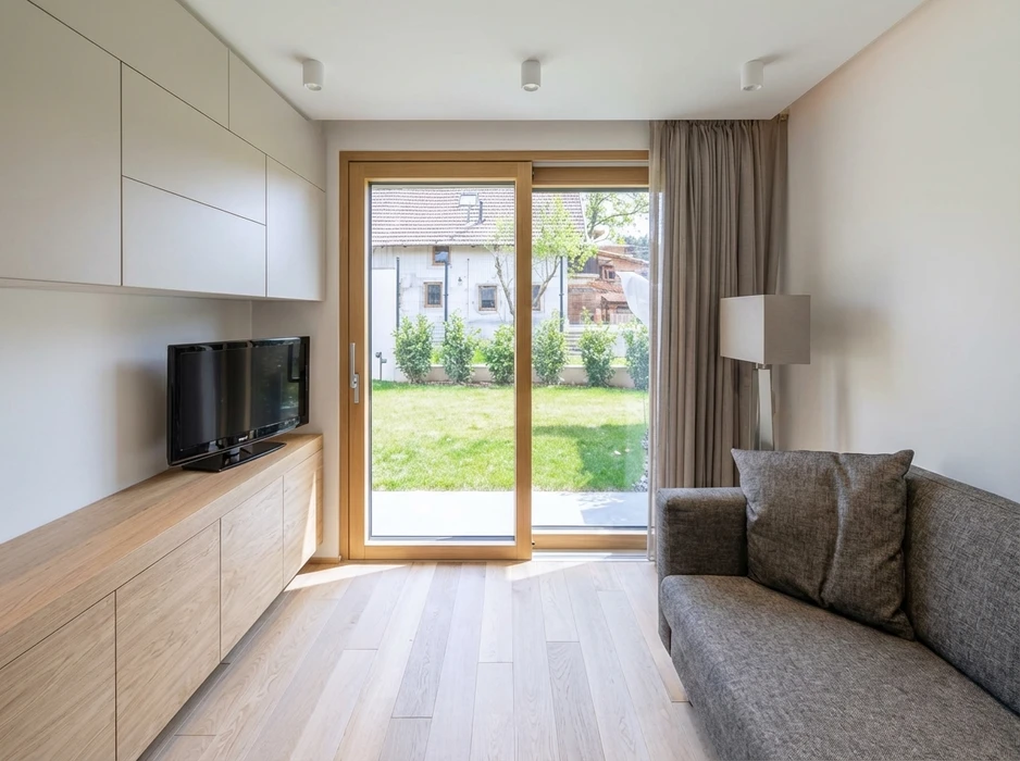 Salon moderne minimaliste avec parquet clair, canapé gris anthracite, meuble TV en bois naturel avec rangements laqués blancs