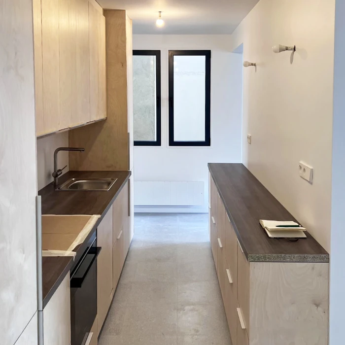 Salon moderne minimaliste avec parquet clair, canapé gris anthracite, meuble TV en bois naturel avec rangements laqués blancs
