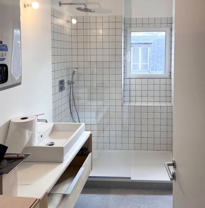 Salle de bain moderne rénovée avec douche à l'italienne, carrelage en pierre naturelle, parois de verre trempé
